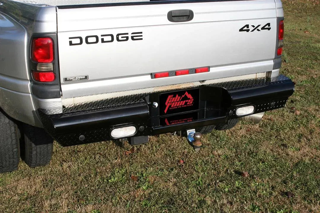 Fab Fours Black Steel Ranch rear bumper with diamond plate on a silver Dodge Ram dually parked on grass, rear three-quarter view