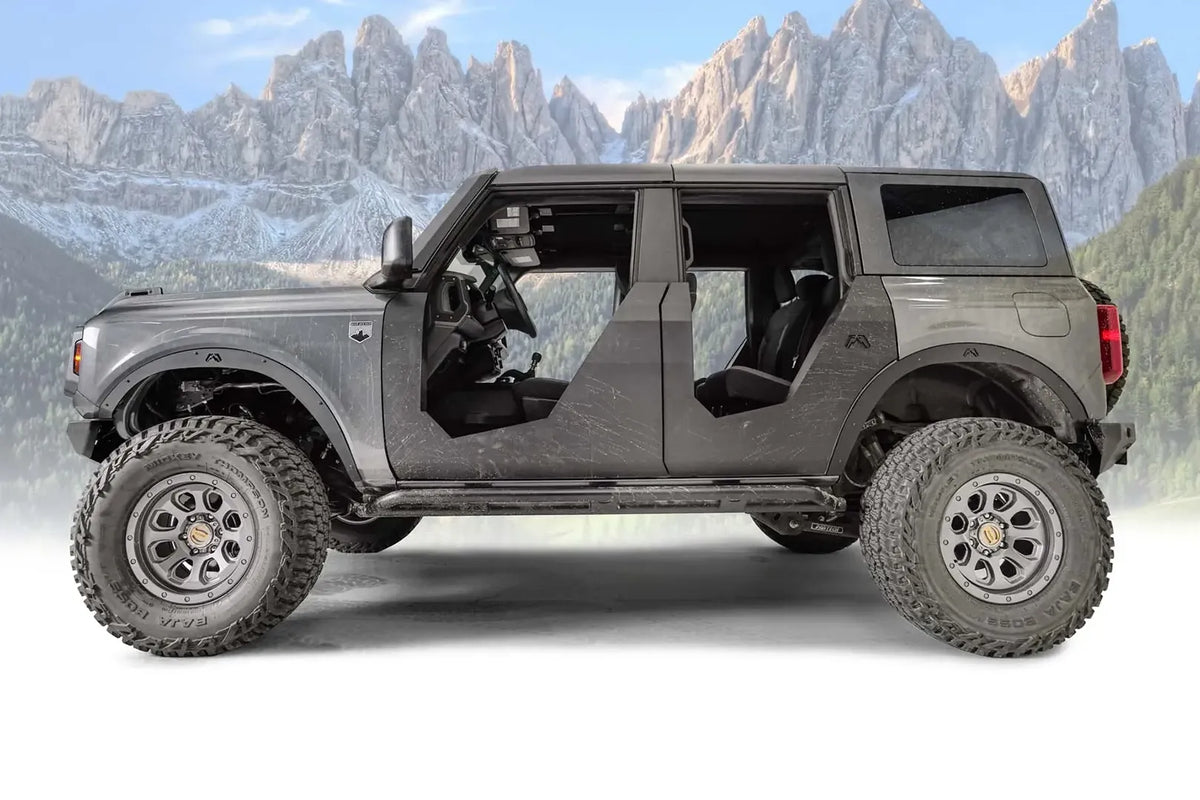 Fab Fours front and rear fender flares on a lifted gray Ford Bronco with doors removed, driver-side profile view with mountain background