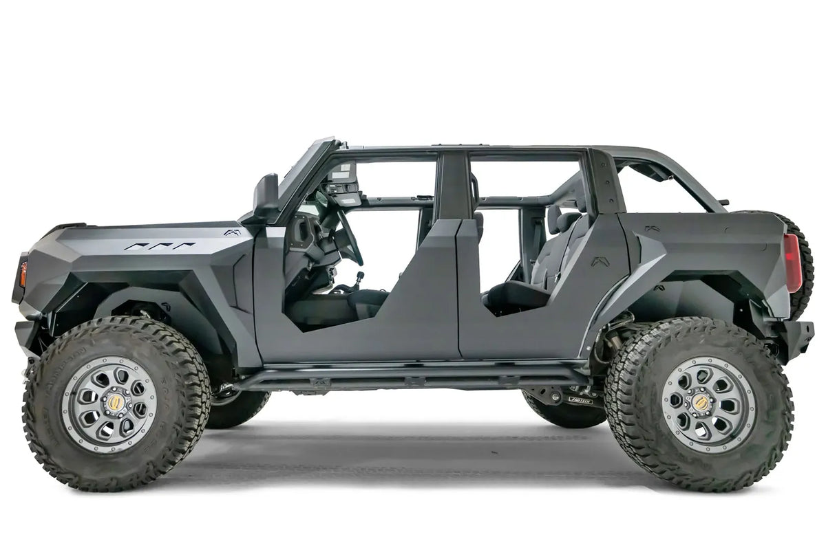 Fab Fours inner fenders on a lifted gray Ford Bronco, driver-side profile view, showing the black steel wheel well liners behind the front and rear tires, with Fab Fours fenders, half doors and rock sliders