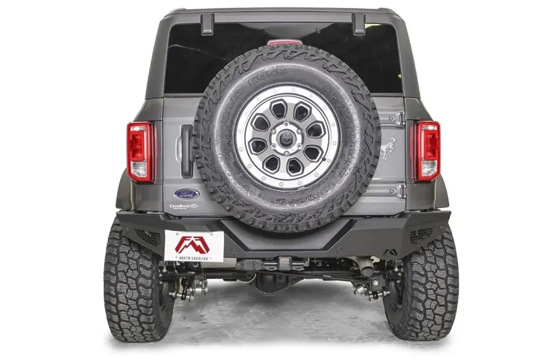 Fab Fours tire carrier relocation bracket on a gray Ford Bronco, rear view, holding the spare tire on the tailgate above a matching Fab Fours rear bumper
