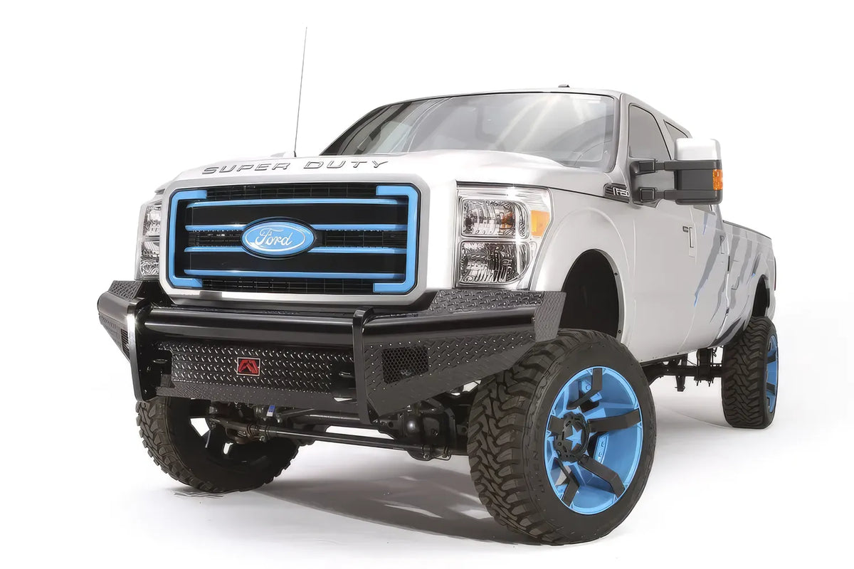 Fab Fours Black Steel front ranch bumper on a silver Ford Super Duty, front driver-side three-quarter view, showing the diamond-plate face, wraparound wing and center logo plate