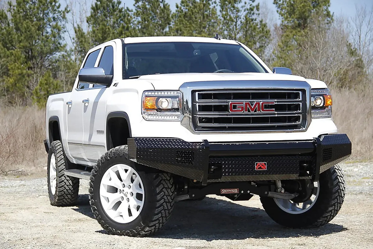 Fab Fours Black Steel front bumper on a white GMC Sierra 1500 parked on gravel, front passenger-side three-quarter view, showing the no-guard diamond-plate face, top tube and wrapped wings