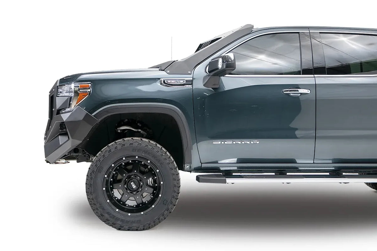 Fab Fours Grumper front bumper and grille on a lifted gray GMC Sierra 1500, driver-side profile view of the bumper end and front wheel