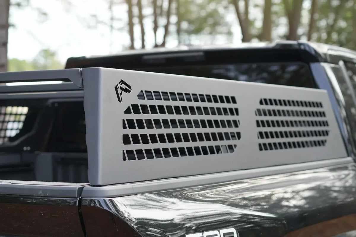 Close-up of a Fab Fours half rack side panel with perforated cutouts and Fab Fours logo on a black Toyota Tacoma