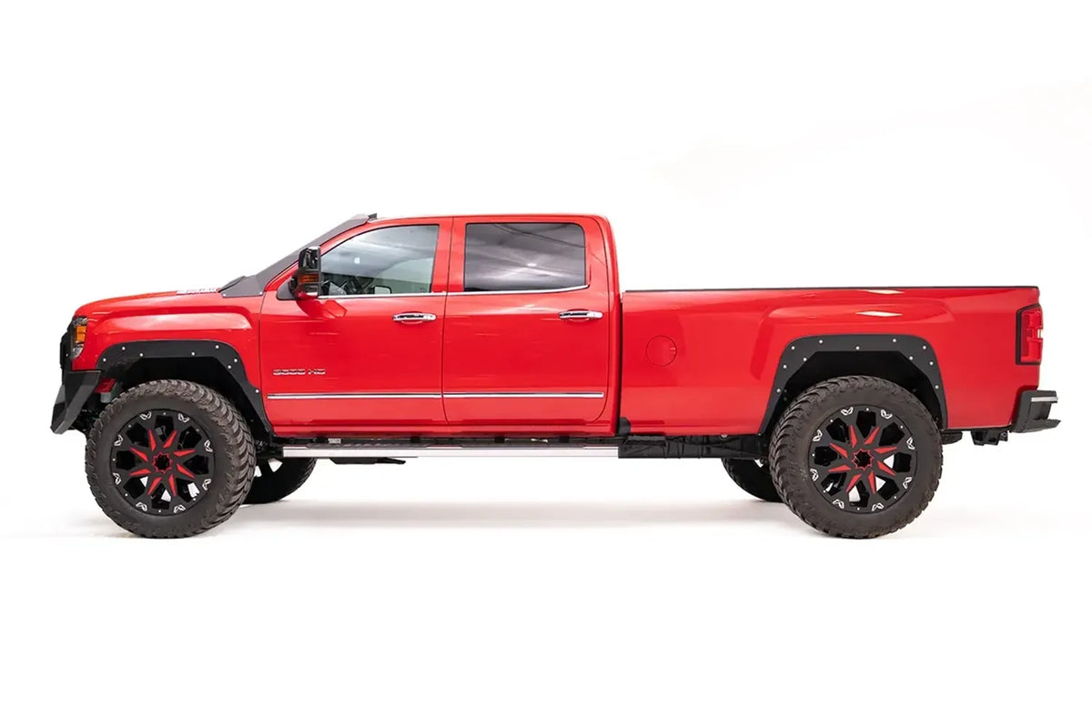 Fab Fours open fender system on the front and rear wheels of a lifted red GMC Sierra 3500HD, driver-side profile view