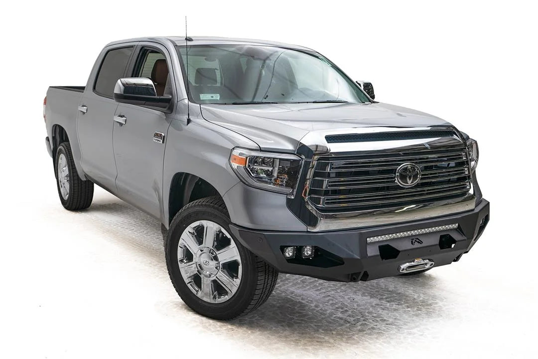 Fab Fours Matrix front bumper on a gray Toyota Tundra, front three-quarter view, showing the no-guard design, light bar opening, and cube light pods