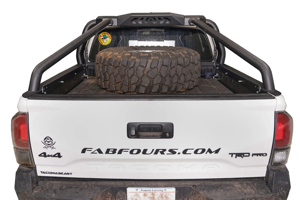 Fab Fours sport rack on a white Toyota Tacoma TRD Pro, straight rear view over the tailgate, with spare tire in the bed and Fab Fours logo cutouts on the center panel