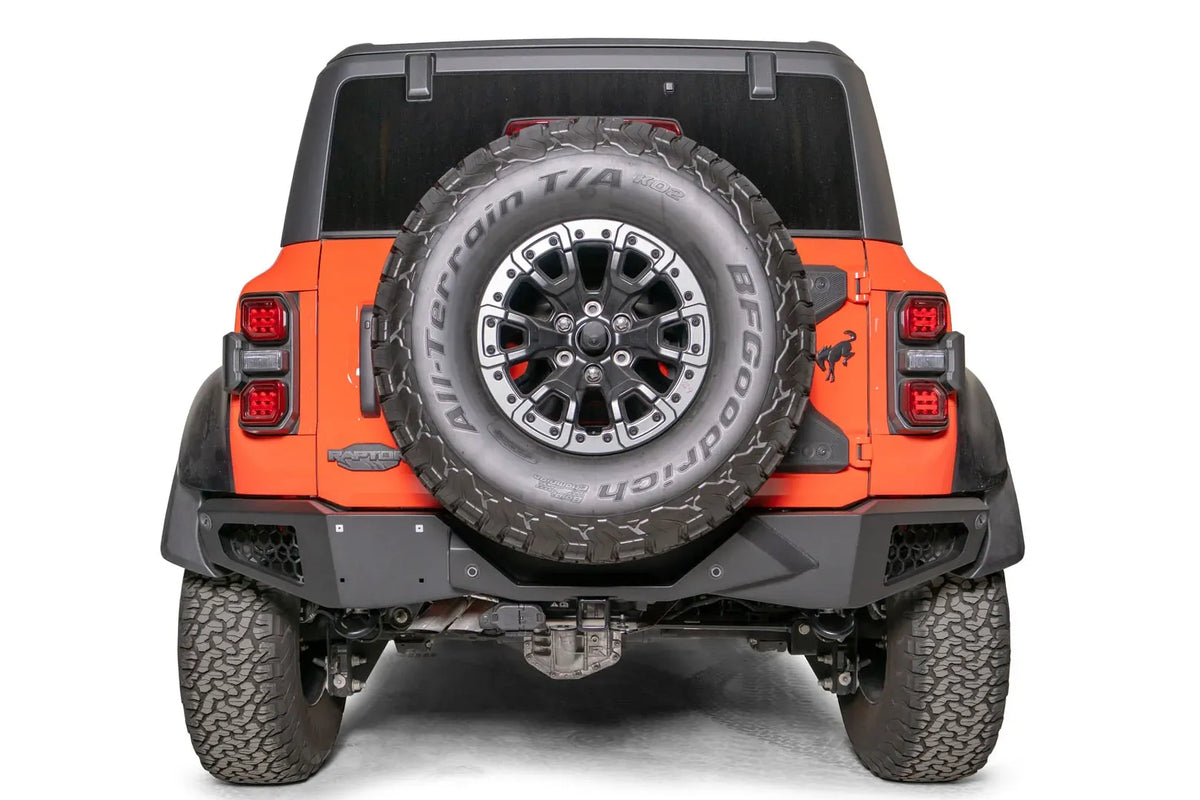 Fab Fours Vengeance rear bumper on an orange Ford Bronco Raptor, straight rear view and tailgate-mounted spare tire