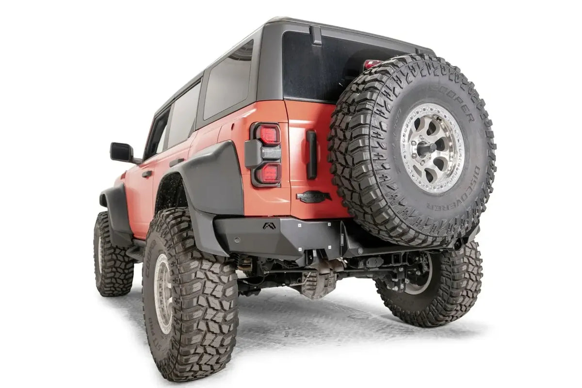 Matte black Fab Fours Premium rear bumper with parking sensors on an orange Ford Bronco Raptor, driver-side rear three-quarter view
