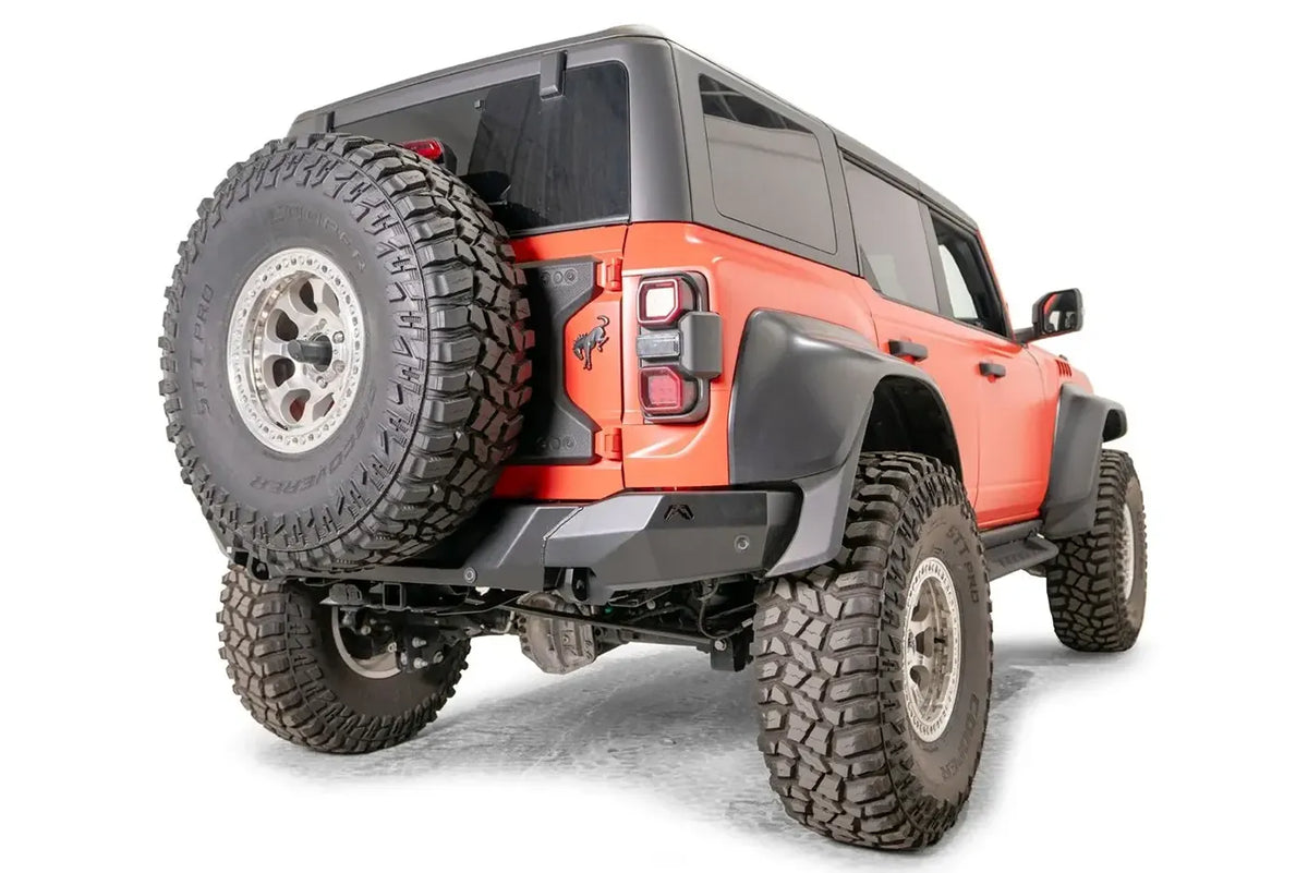 Matte black Fab Fours Premium rear bumper with parking sensors on an orange Ford Bronco Raptor, passenger-side rear three-quarter view
