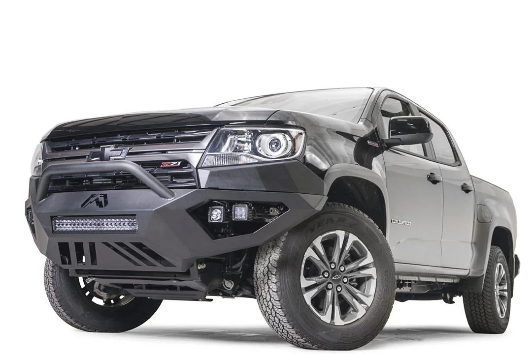 Fab Fours Vengeance front bumper with pre-runner guard on a black Chevrolet Colorado, driver-side front three-quarter view, with LED light bar and dual cube lights