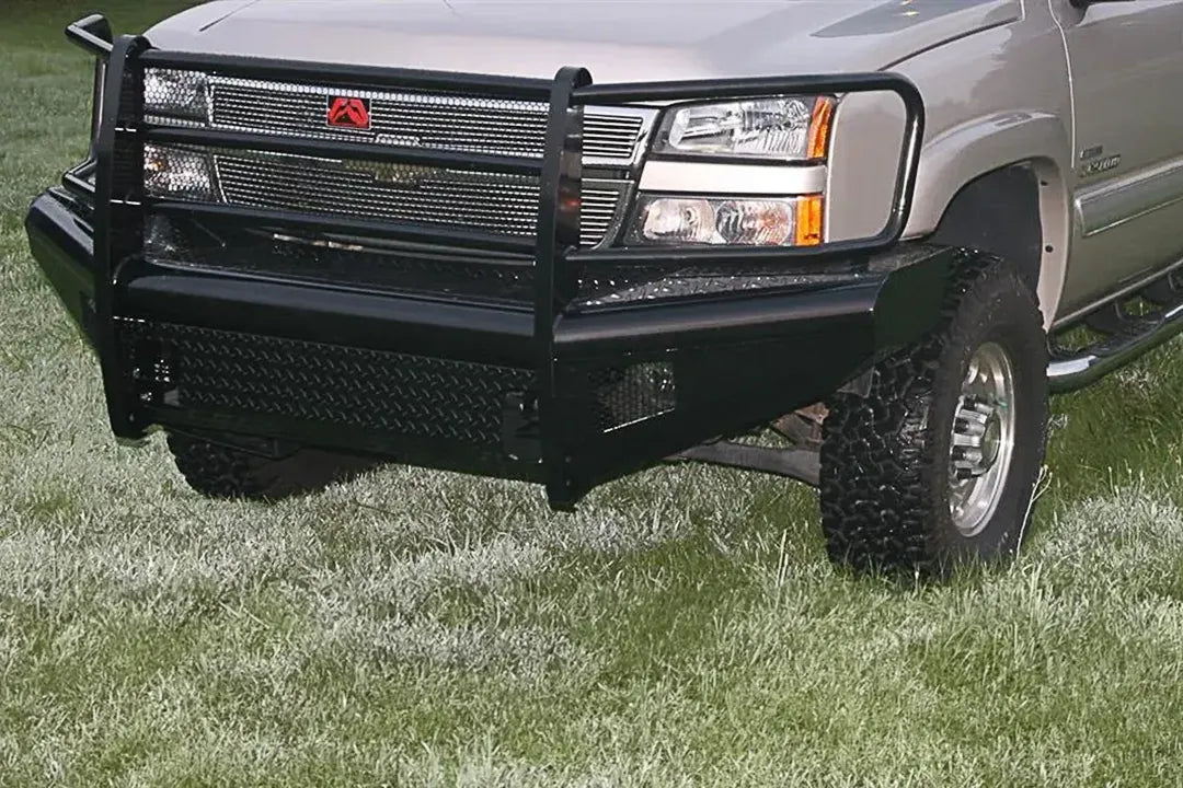Fab Fours Black Steel front bumper with full guard on a silver Chevrolet Silverado 2500HD, close-up front outdoor view, showing the full grille guard with mesh insert, diamond-plate bumper face and Fab Fours logo