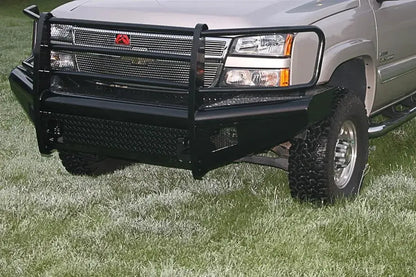 Fab Fours Black Steel front bumper with full guard on a silver Chevrolet Silverado 2500HD, close-up front outdoor view, showing the full grille guard with mesh insert, diamond-plate bumper face and Fab Fours logo