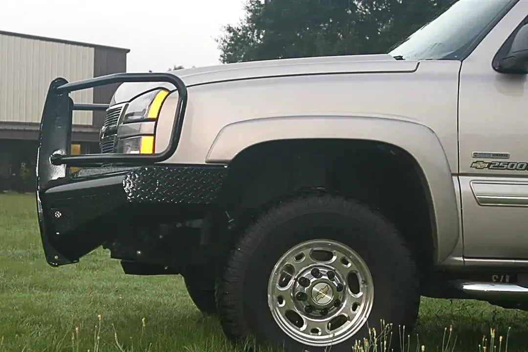 Fab Fours Black Steel front bumper with full guard on a silver Chevrolet Silverado 2500HD, front driver-side outdoor view, showing the full grille guard hoop, diamond-plate bumper top and wrap-around end