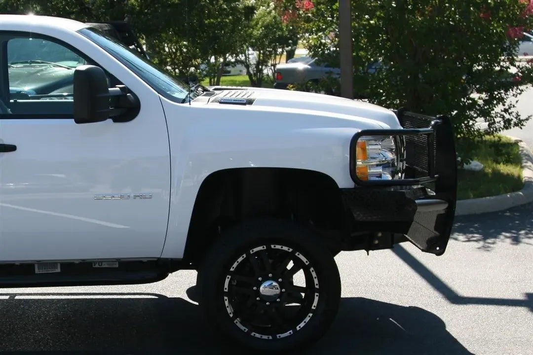 Fab Fours Black Steel front bumper with full guard on a white Chevrolet Silverado 2500HD, passenger-side profile outdoor view, showing the full grille guard side hoop and wrap-around bumper end