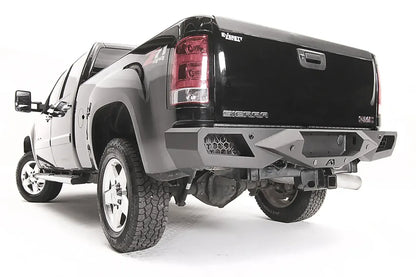 Fab Fours Vengeance rear bumper on a black GMC Sierra 2500HD, rear driver-side three-quarter view, showing the honeycomb light pods, angular end caps and Fab Fours logo