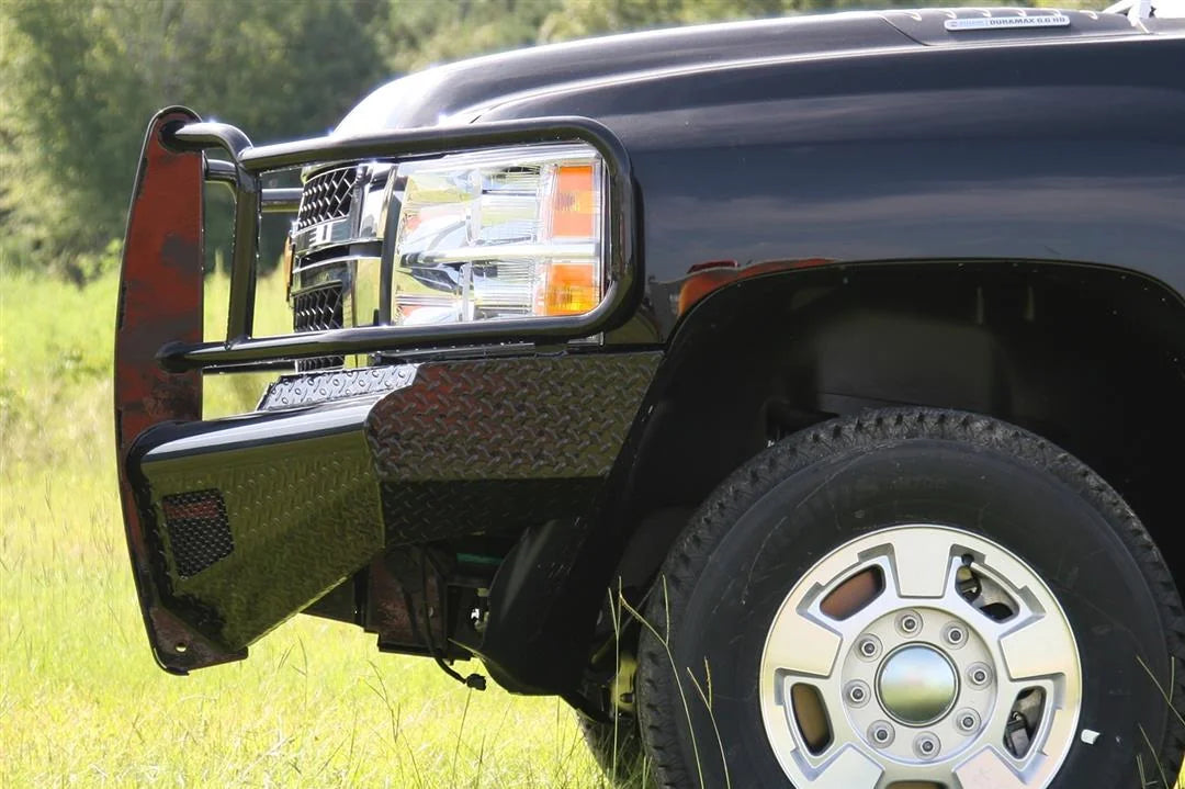 Fab Fours Black Steel front bumper with full guard on a black Chevrolet Silverado 2500HD, close-up corner outdoor view, showing the full grille guard side hoop and diamond-plate wrap-around end