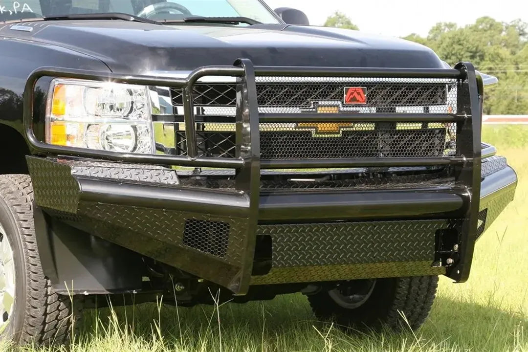 Fab Fours Black Steel front bumper with full guard on a black Chevrolet Silverado 2500HD, close-up front outdoor view, showing the full grille guard with mesh insert, diamond-plate bumper face and Fab Fours logo