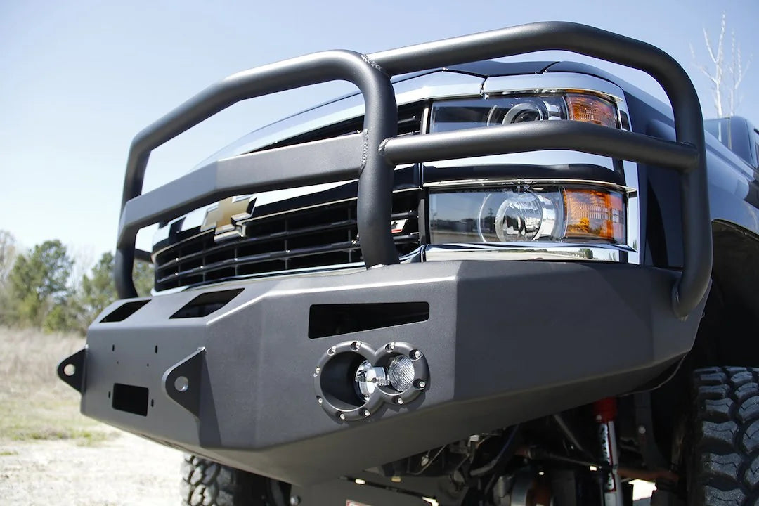 Close-up of Fab Fours Premium heavy-duty winch front bumper with full grille guard on a black Chevrolet Silverado 2500HD