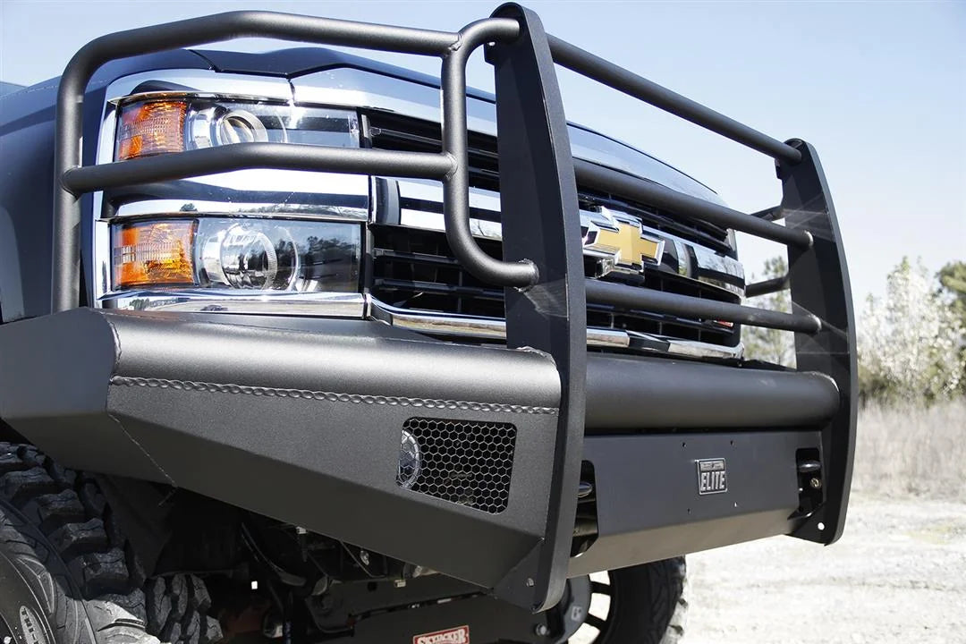 Fab Fours Black Steel Elite front bumper with full guard on a black Chevrolet Silverado 2500HD, close-up front corner view, showing the full grille guard tubing, Elite badge and mesh light opening