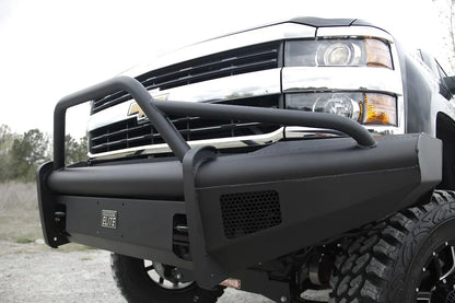 Fab Fours Black Steel Elite front bumper with pre-runner guard on a black Chevrolet Silverado 2500HD, close-up outdoor view, showing the pre-runner guard tubing, Elite badge and mesh light opening