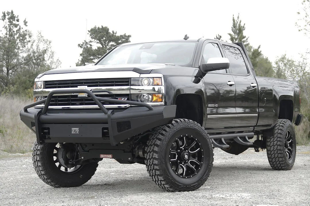 Fab Fours Black Steel Elite front bumper with pre-runner guard on a black Chevrolet Silverado 2500HD, front driver-side three-quarter outdoor view, showing the pre-runner guard, smooth-plate bumper face and Elite badge
