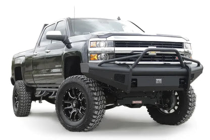 Fab Fours Black Steel Elite front bumper with pre-runner guard on a black Chevrolet Silverado 2500HD, front passenger-side three-quarter view on a white background, showing the pre-runner guard, smooth-plate bumper face and Elite badge