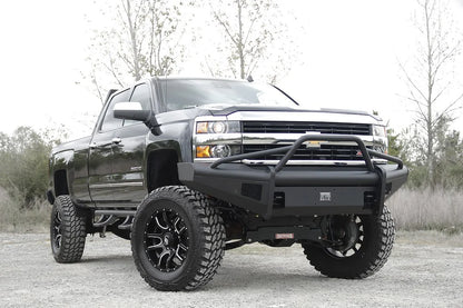 Fab Fours Black Steel Elite front bumper with pre-runner guard on a black Chevrolet Silverado 2500HD, front passenger-side three-quarter outdoor view, showing the pre-runner guard, smooth-plate bumper face and Elite badge