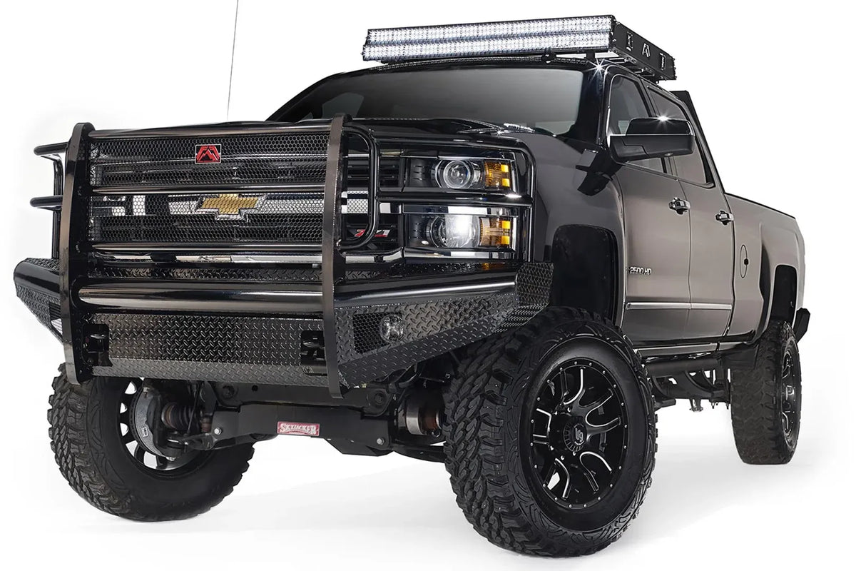Fab Fours Black Steel front bumper with full guard on a black Chevrolet Silverado 2500HD, front passenger-side three-quarter view, showing the full grille guard with mesh insert, diamond-plate bumper face and Fab Fours logo