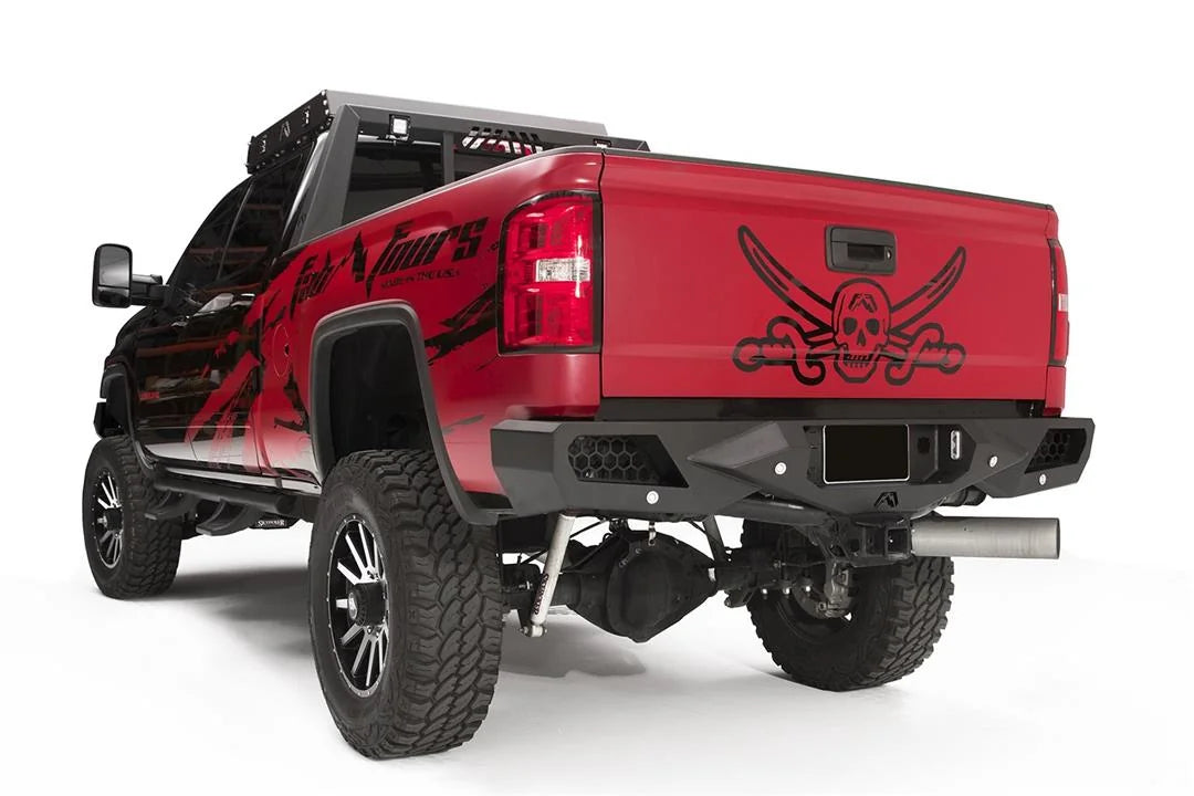 Fab Fours Vengeance rear bumper on a red GMC Sierra 2500HD, rear driver-side three-quarter view, showing the honeycomb light pods, angular end caps and license plate recess