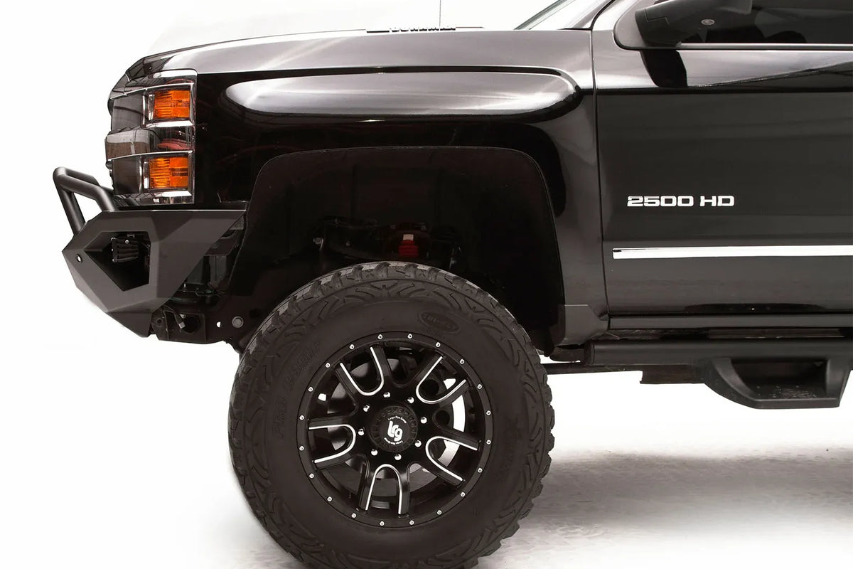 Fab Fours Vengeance front bumper with pre-runner guard on a black Chevrolet Silverado 2500HD, close-up front corner driver-side view, showing the pre-runner guard tubing, angular bumper end and wheel clearance