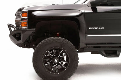 Fab Fours Vengeance front bumper with pre-runner guard on a black Chevrolet Silverado 2500HD, close-up front corner driver-side view, showing the pre-runner guard tubing, angular bumper end and wheel clearance
