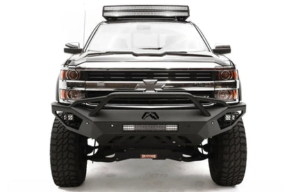 Fab Fours Vengeance front bumper with pre-runner guard on a black Chevrolet Silverado 2500HD, straight-on front view, showing the pre-runner guard tubing, Fab Fours logo, cube light pods and center light bar
