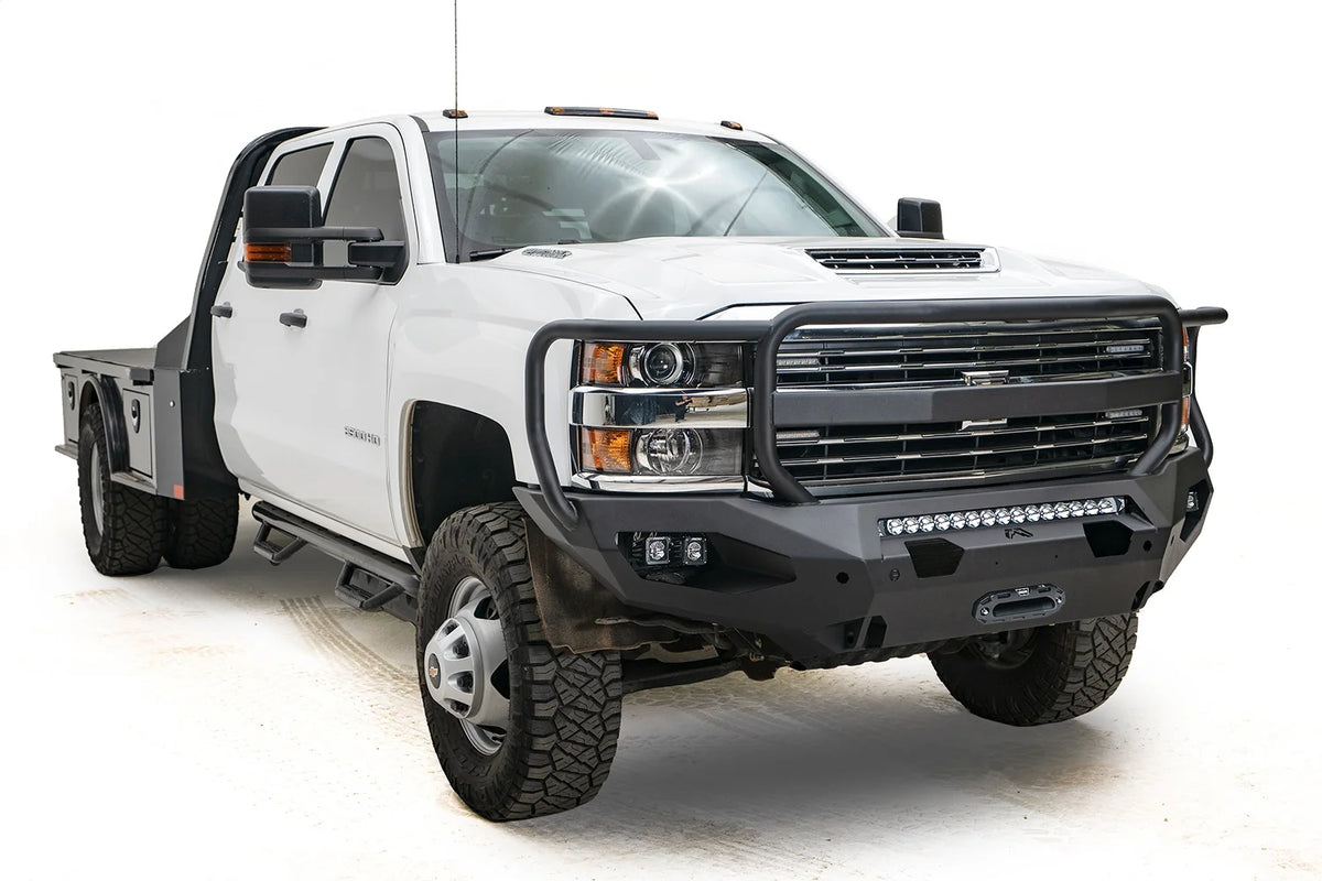 Fab Fours Matrix front bumper with full guard on a white Chevrolet Silverado 3500HD, front driver-side three-quarter view, showing the full grille guard, center light bar, cube light pods and winch fairlead