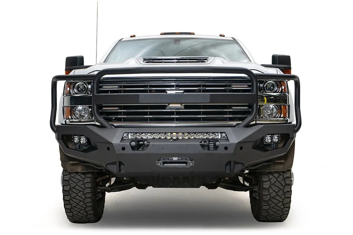 Fab Fours Matrix front bumper with full guard on a white Chevrolet Silverado 3500HD, straight-on front view, showing the full grille guard hoops, center light bar, cube light pods and winch fairlead