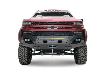 Fab Fours Matrix front bumper on a red Chevrolet Silverado, straight-on front view, showing the pre-runner guard tubing, hex light cutouts, winch fairlead opening and Fab Fours logo