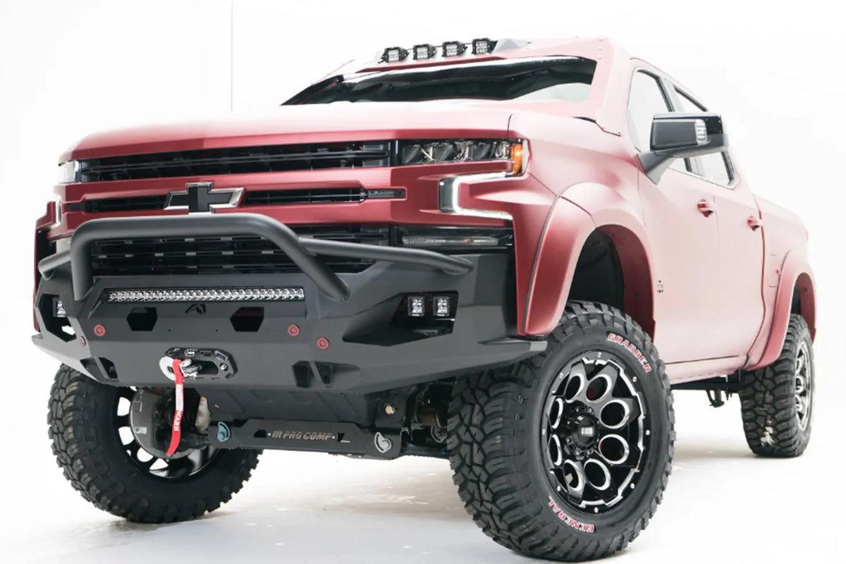 Fab Fours Matrix front bumper with pre-runner guard on a red Chevrolet Silverado, front driver-side three-quarter view, showing the pre-runner guard, center light bar, cube light pods and winch