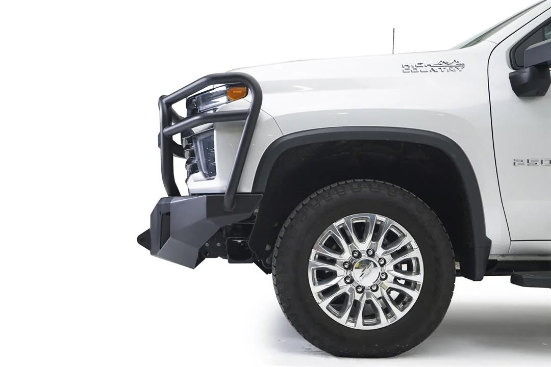 Fab Fours Premium Winch front bumper with full guard on a white Chevrolet Silverado 2500HD, close-up front corner view from the driver side, showing the full grille guard, the angular bumper end and wheel clearance