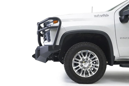 Fab Fours Premium Winch front bumper with full guard on a white Chevrolet Silverado 2500HD, close-up front corner view from the driver side, showing the full grille guard, the angular bumper end and wheel clearance