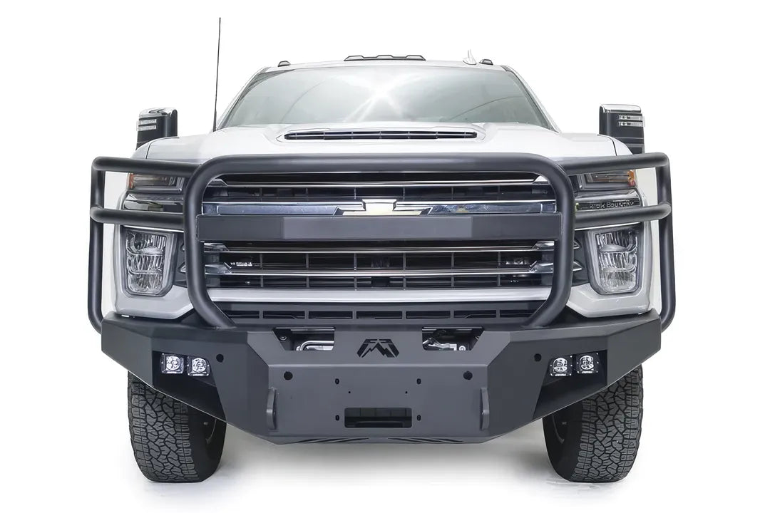 Fab Fours Premium Winch front bumper with full guard on a white Chevrolet Silverado 2500HD, straight-on front view, showing the full grille guard, the center winch plate, Fab Fours logo and cube light pods