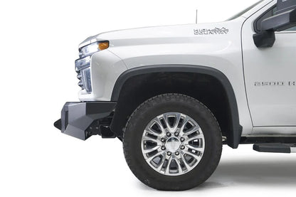 Fab Fours Premium Winch front bumper on a white Chevrolet Silverado 2500HD, close-up front corner view from the driver side, showing the angular bumper end and wheel clearance