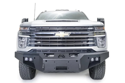 Fab Fours Premium Winch front bumper on a white Chevrolet Silverado 2500HD, straight-on front view, showing the center winch plate, Fab Fours logo and cube light pods