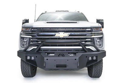 Fab Fours Premium Winch front bumper with pre-runner guard on a white Chevrolet Silverado 2500HD, straight-on front view, showing the pre-runner guard, the center winch plate, Fab Fours logo and cube light pods