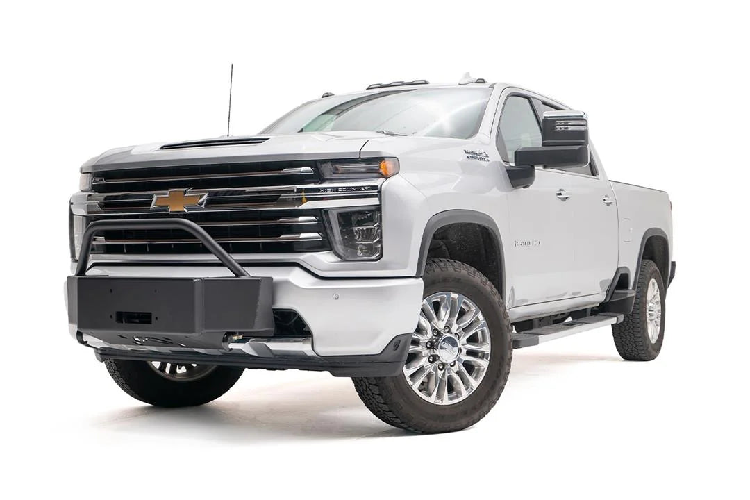 Fab Fours winch mount with pre-runner guard on a white Chevrolet Silverado 2500HD, front driver-side three-quarter view, showing the pre-runner hoop, winch mount plate and fairlead opening
