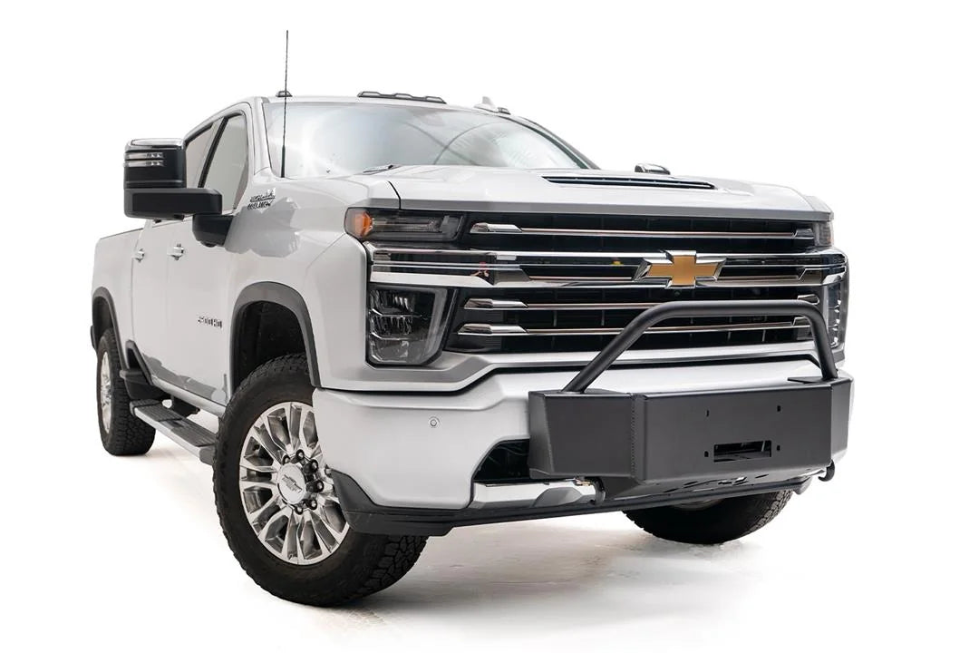 Fab Fours winch mount with pre-runner guard on a white Chevrolet Silverado 2500HD, front passenger-side three-quarter view, showing the pre-runner hoop, winch mount plate and fairlead opening
