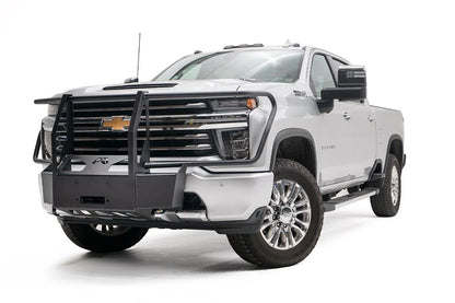 Fab Fours winch mount with full guard on a white Chevrolet Silverado 2500HD, front driver-side three-quarter view, showing the full grille guard uprights, winch mount plate and Fab Fours logo