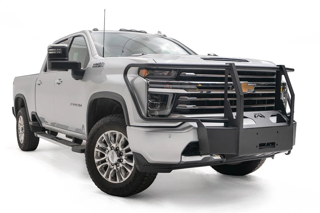 Fab Fours winch mount with full guard on a white Chevrolet Silverado 2500HD, front passenger-side three-quarter view, showing the full grille guard uprights, winch mount plate and Fab Fours logo
