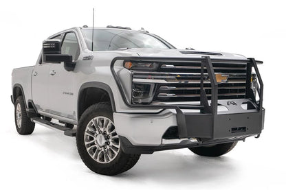 Fab Fours winch mount with full guard on a white Chevrolet Silverado 2500HD, front passenger-side three-quarter view, showing the full grille guard uprights, winch mount plate and Fab Fours logo