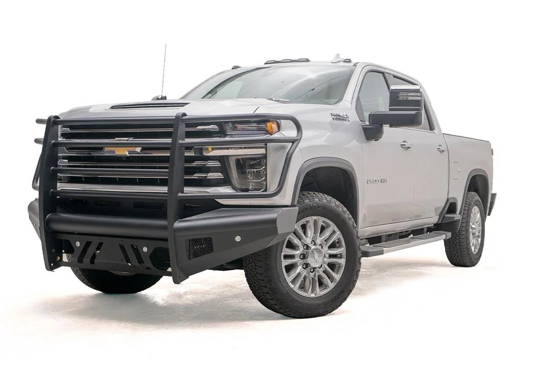 Fab Fours Black Steel Elite front bumper with full guard on a silver Chevrolet Silverado 2500HD, front driver-side three-quarter view, showing the full grille guard, slotted skid plate and mesh light openings