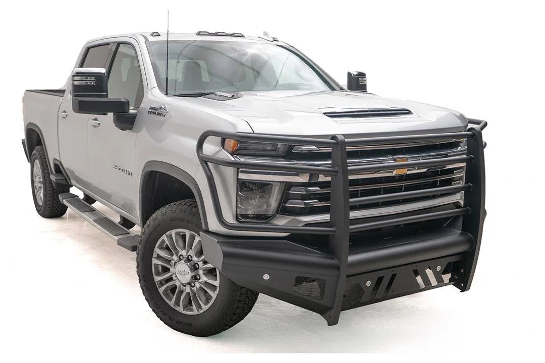 Fab Fours Black Steel Elite front bumper with full guard on a silver Chevrolet Silverado 2500HD, front passenger-side three-quarter view, showing the full grille guard, slotted skid plate and mesh light openings